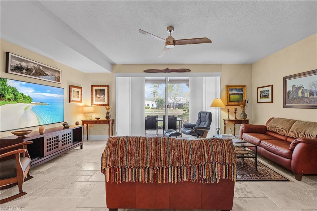 5677 Cove Circle Naples, FL 34119 - Photo 6 of 26 a living room with furniture a flat screen tv and a window
