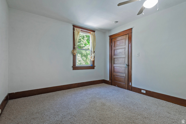 178 17th Street Ogden, UT 84404 - Photo 21 of 29 Carpeted room featuring a ceiling fan with light, a window with wood trim, and a paneled wood door with matching trim and baseboards