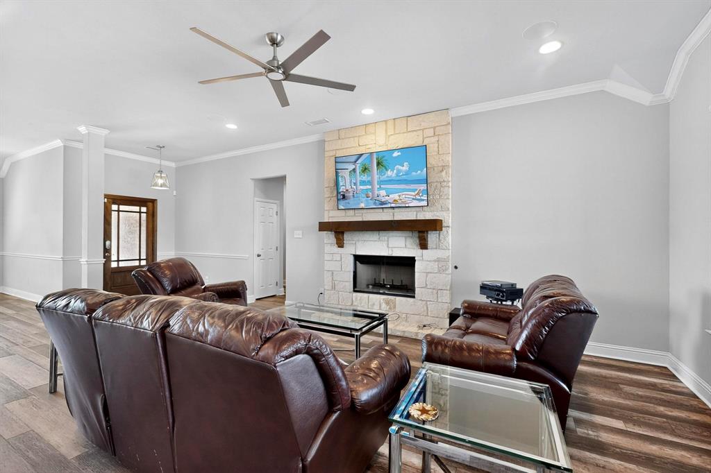 634 Gant Road Sherman, TX 75090 - Photo 11 of 40 Living space featuring a stone-clad fireplace with a wood mantel, wood-finish flooring, and a ceiling fan