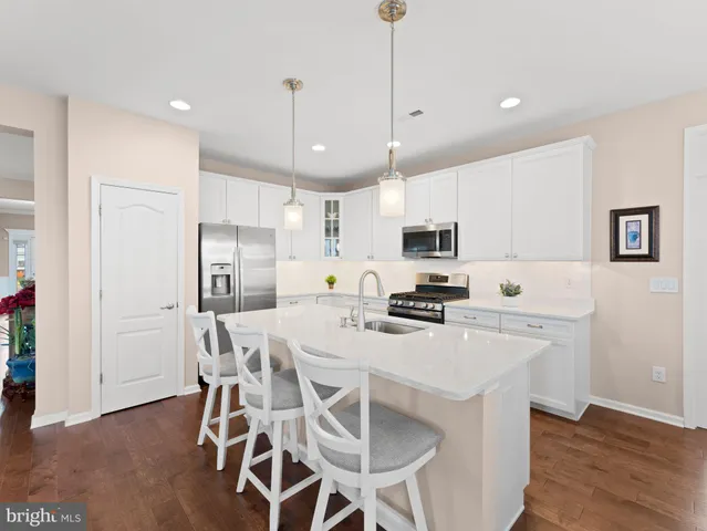 a kitchen with stainless steel appliances a stove a refrigerator a microwave oven a sink a dining table and chairs