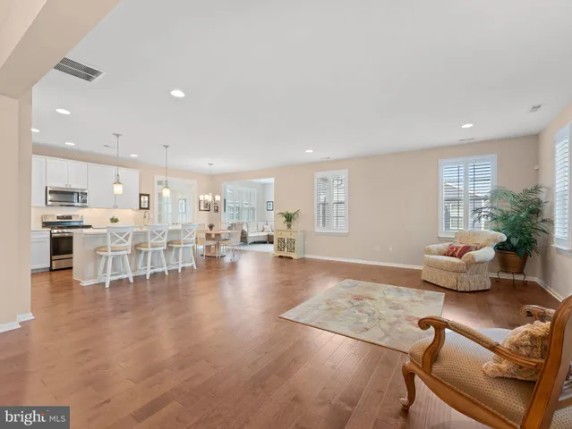 a living room with furniture and kitchen view with wooden floor