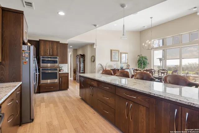 a large kitchen with granite countertop a large counter top stainless steel appliances and cabinets