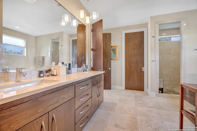 a spacious bathroom with a double vanity sink a mirror and a shower