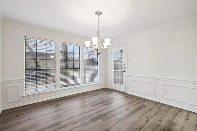 a view of a room with wooden floor chandelier and windows