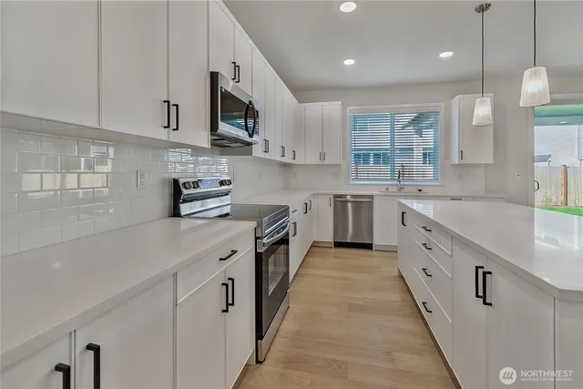 a large white kitchen with stainless steel appliances granite countertop lots of counter space sink and cabinets