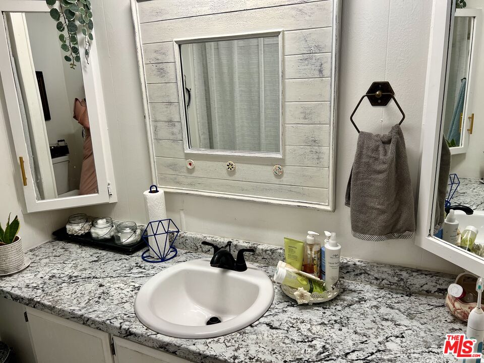 2744 West Rialto Avenue, Unit 49 Rialto, CA 92376 - Photo 17 of 40 a bathroom with a granite countertop sink and a mirror