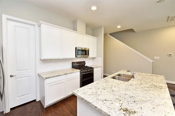 a kitchen with a refrigerator stove and white cabinets with wooden floor