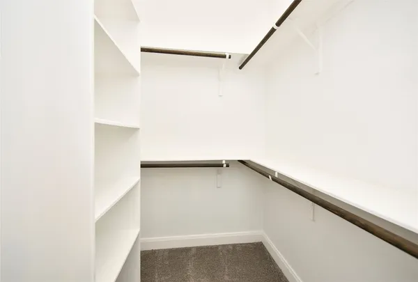 a view of an empty walk in closet with wooden floor