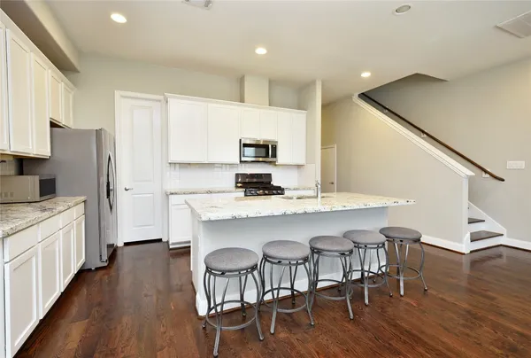 a kitchen with stainless steel appliances granite countertop a dining table chairs stove refrigerator and cabinets