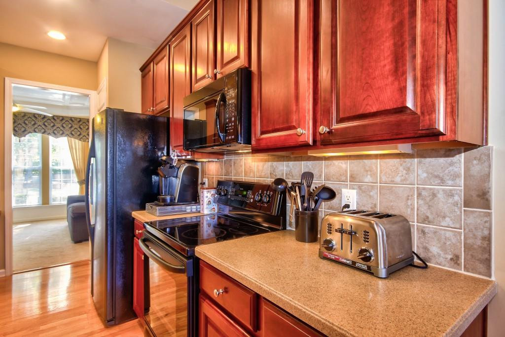 7725 Monte Alto Drive Raleigh, NC 27613 - Photo 8 of 25 Beautiful tile back splash and Corian counter tops along with the darker cabinets creates elegance in this kitchen. Kitchen