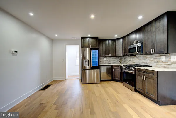 a kitchen with granite countertop wooden cabinets a refrigerator and a stove top oven