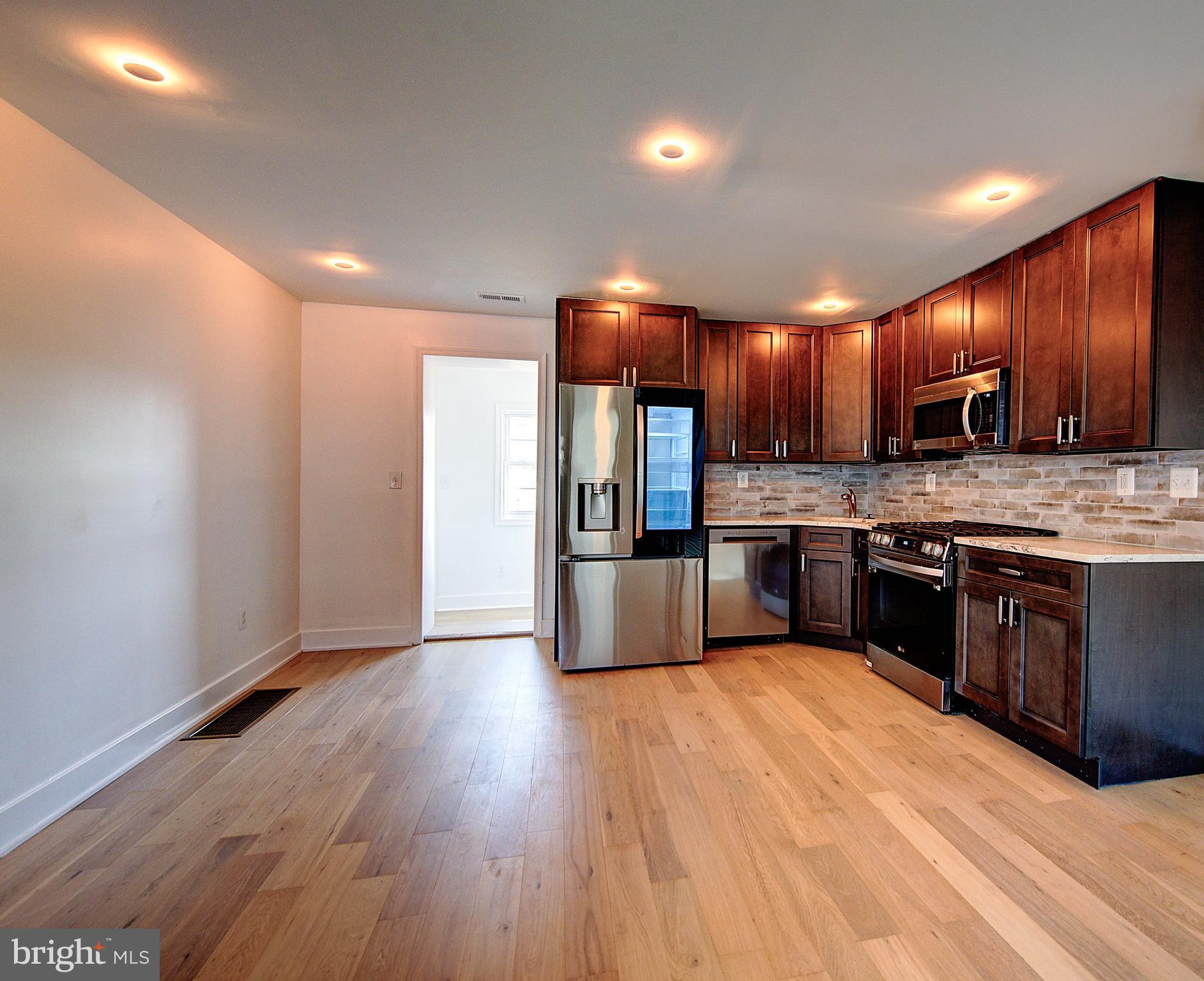 5736 Reedland Street Philadelphia, PA 19143 - Photo 6 of 22 a large kitchen with a sink and dishwasher a stove top oven with wooden floor