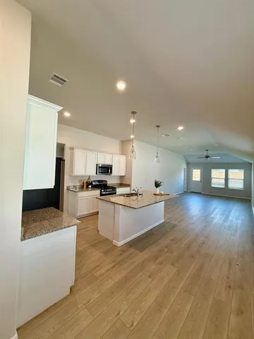 a large kitchen with stainless steel appliances kitchen island a large counter top and a wooden floors