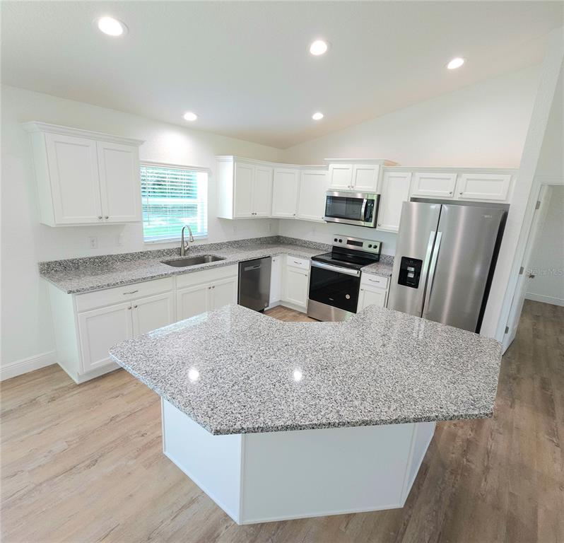 3068 Southwest 131st Place Road Ocala, FL 34473 - Photo 2 of 12 a kitchen with stainless steel appliances granite countertop a stove a sink a microwave a refrigerator and white cabinets with wooden floor