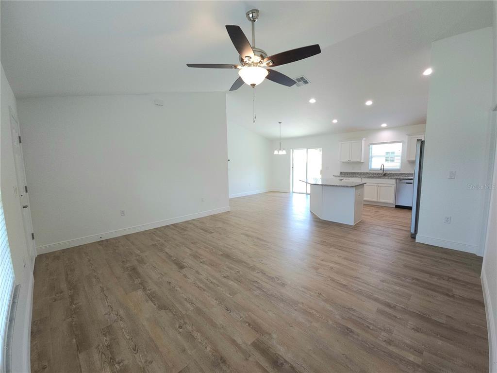 3068 Southwest 131st Place Road Ocala, FL 34473 - Photo 4 of 12 a view of an empty room and a kitchen with wooden floor