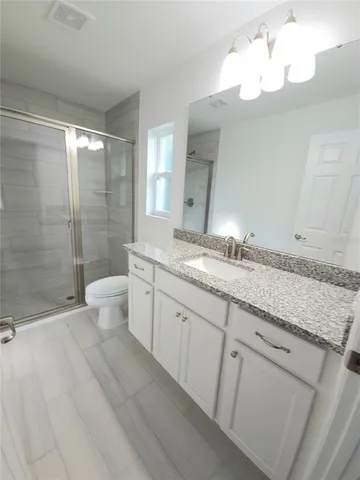 a bathroom with a granite countertop sink a toilet and shower