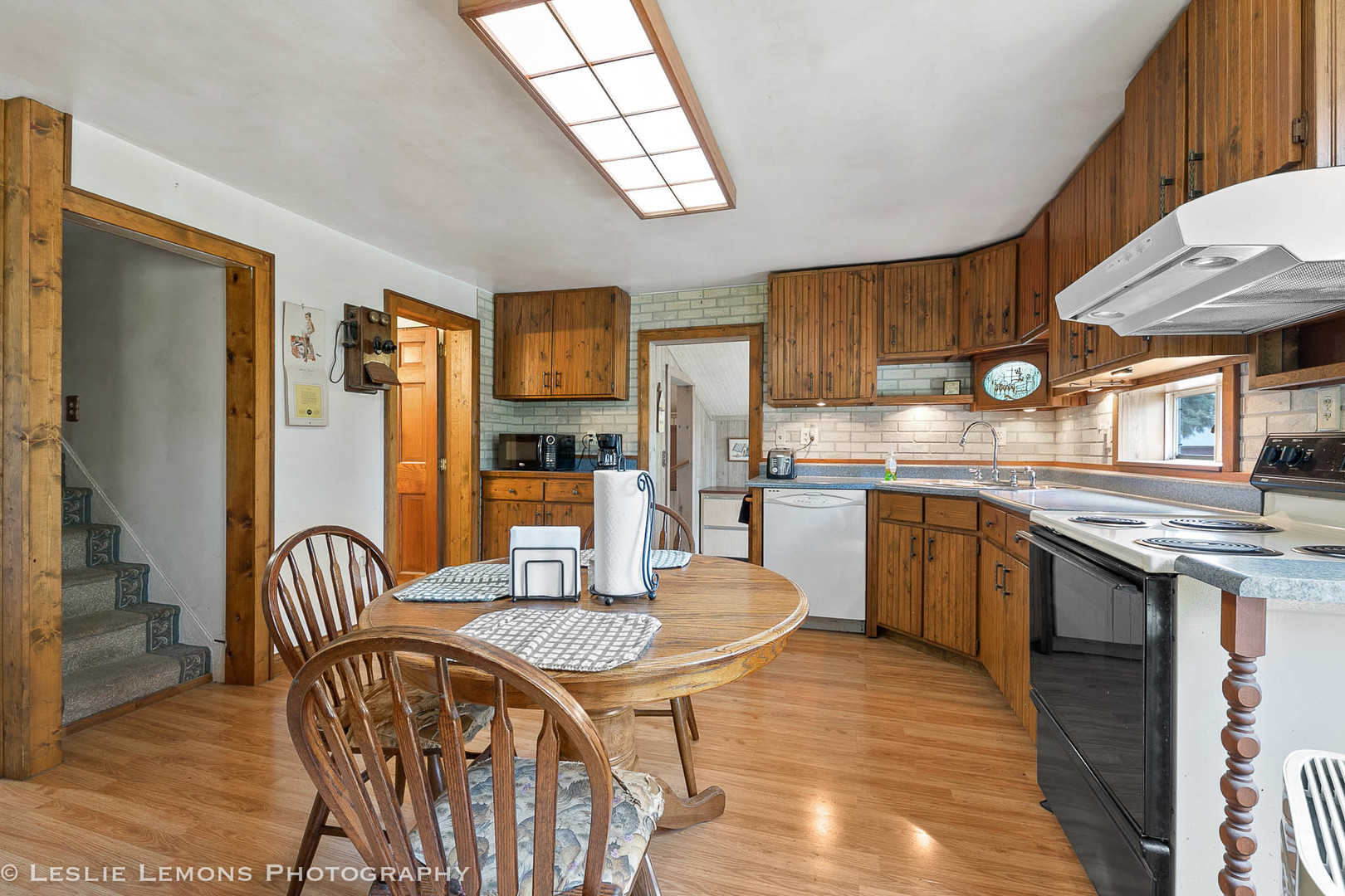 16276 Willrett Road Malta, IL 60150 - Photo 7 of 25 a kitchen with stainless steel appliances granite countertop a stove top oven a sink a dining table and chairs with wooden floor