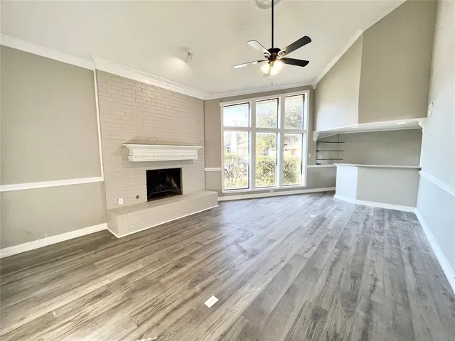 an empty room with wooden floor fireplace and windows