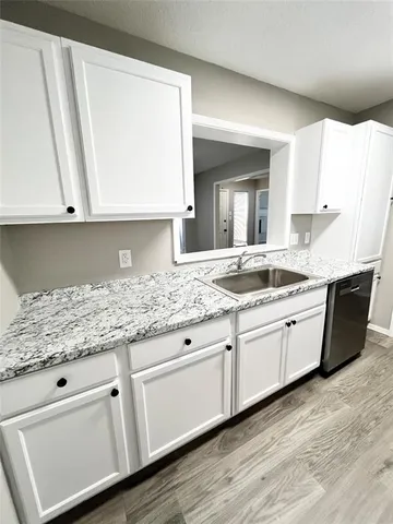 a kitchen with granite countertop white cabinets and sink