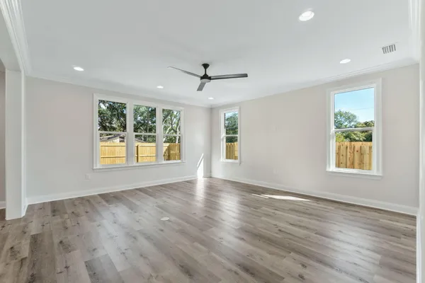an empty room with wooden floor and windows