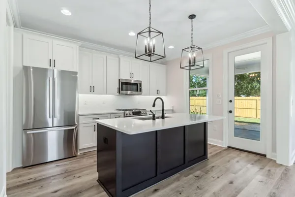 a kitchen with stainless steel appliances granite countertop a refrigerator a sink dishwasher a kitchen island with wooden cabinets and floors
