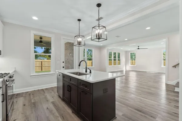 a kitchen with stainless steel appliances granite countertop wooden floors and chandelier