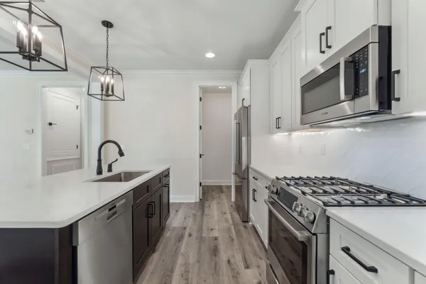 a kitchen that has a sink stainless steel appliances and cabinets