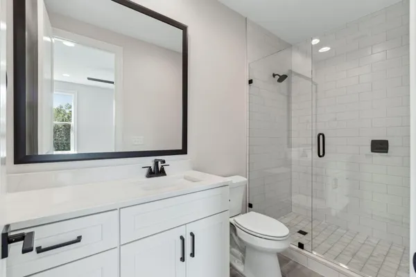 a bathroom with a sink a toilet a mirror and shower