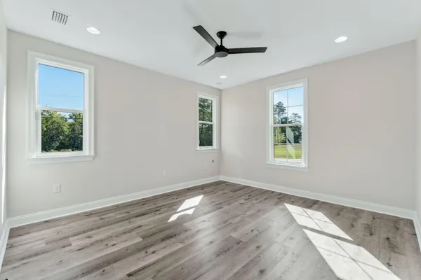 a view of empty room with wooden floor and fan