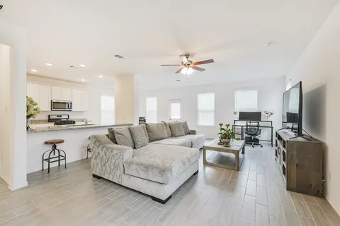 a living room with furniture kitchen view and a flat screen tv