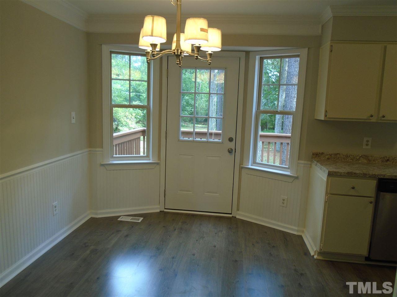 3241 Banks Road Raleigh, NC 27603 - Photo 4 of 19 an empty room with wooden floor a chandelier fan and windows