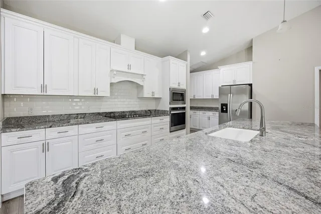 a kitchen with granite countertop a stove a sink and a refrigerator