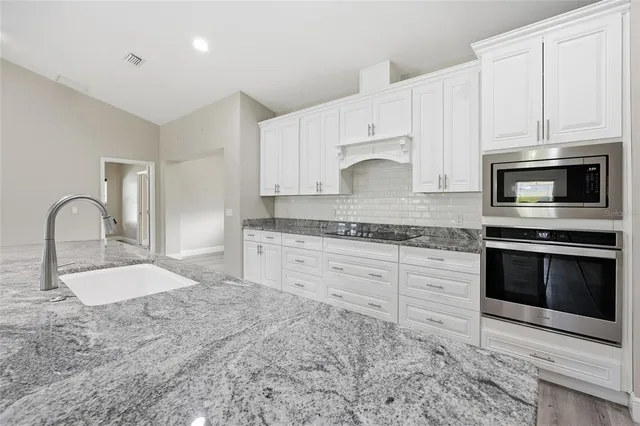 a kitchen with granite countertop a stove a sink and a microwave