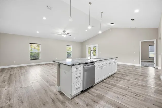 a large kitchen with stainless steel appliances granite countertop a large center island and a wooden floors