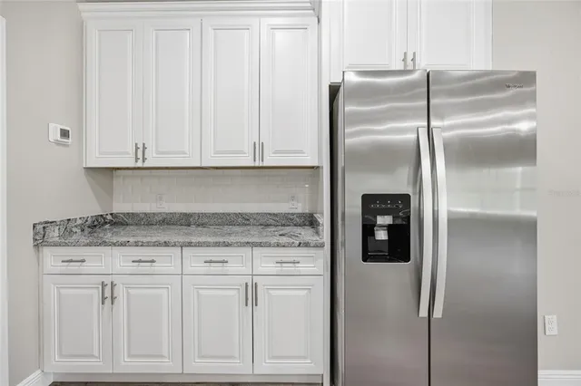 a kitchen with granite countertop a refrigerator sink and cabinets