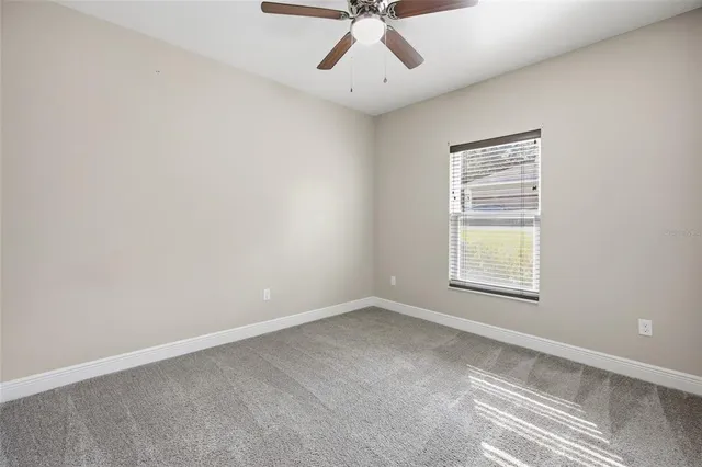 an empty room with a ceiling fan and window