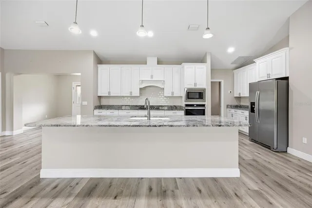 a large kitchen with granite countertop a large counter top stainless steel appliances and cabinets