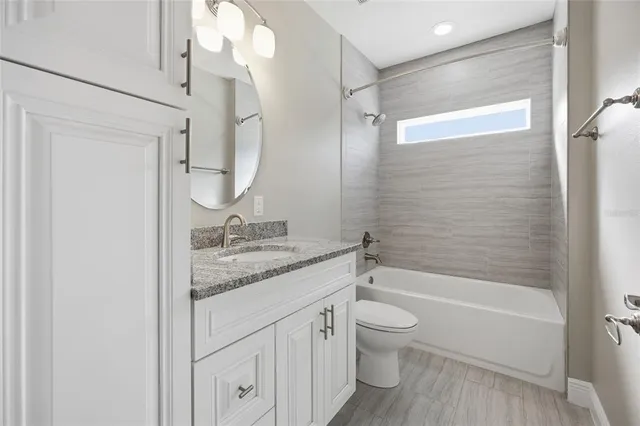 a bathroom with a granite countertop sink a toilet and shower