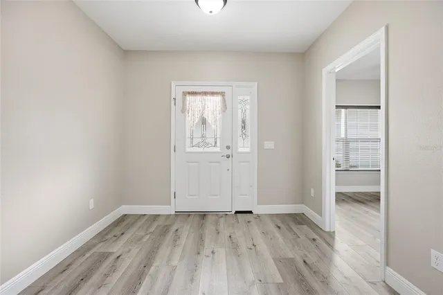an empty room with wooden floor closet and windows
