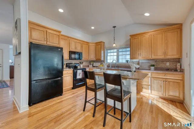 a kitchen with stainless steel appliances granite countertop a refrigerator a stove top oven a sink dishwasher and white cabinets with wooden floor