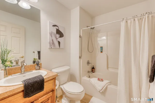 a bathroom with a granite countertop bathtub shower sink vanity mirror and toilet