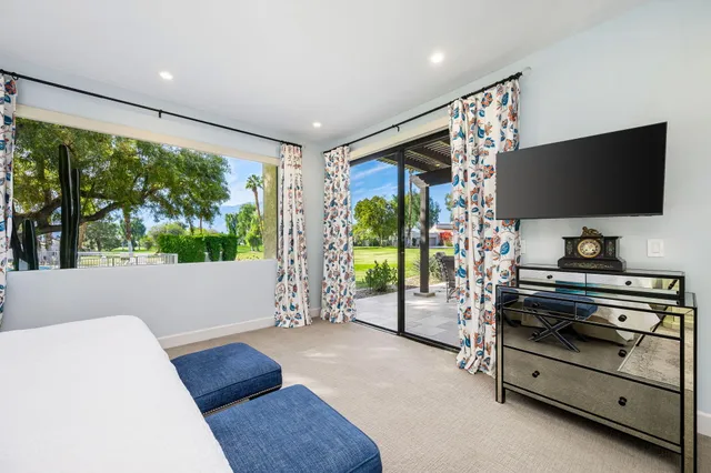 a living room with furniture a flat tv screen and a floor to ceiling window