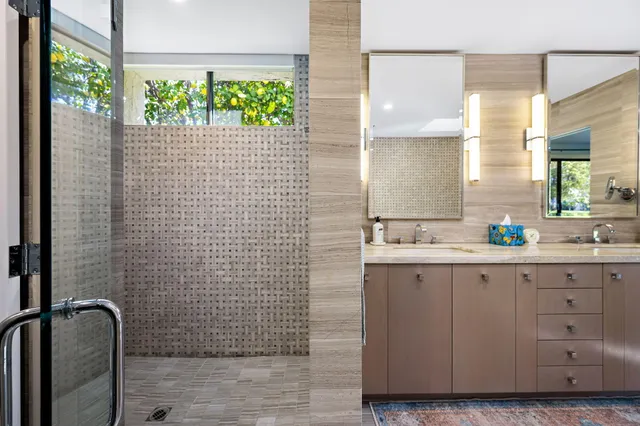 a bathroom with a granite countertop sink a toilet a mirror and shower