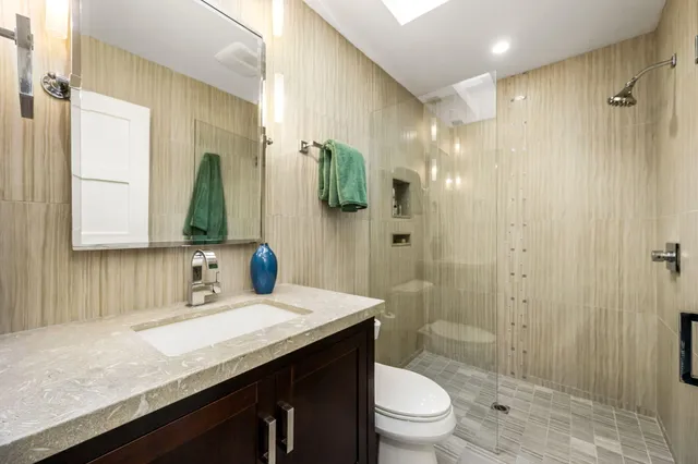 a bathroom with a granite countertop sink a toilet and shower