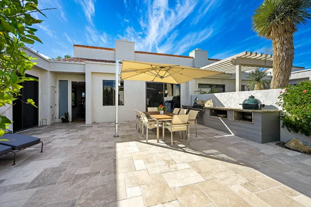 a view of a patio with a table and chairs under an umbrella