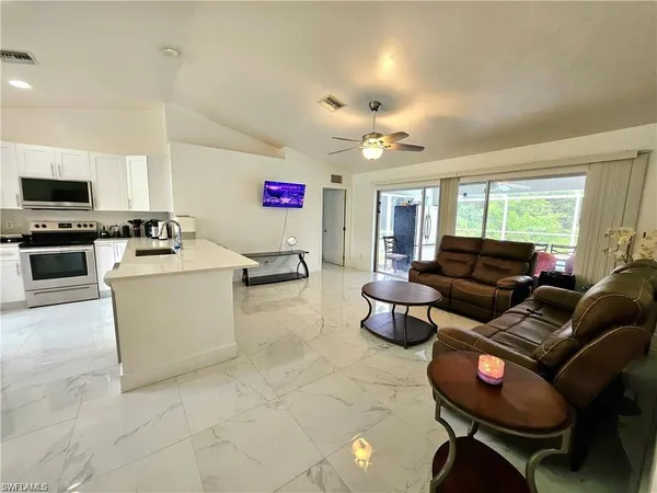a living room with furniture a flat screen tv and kitchen view