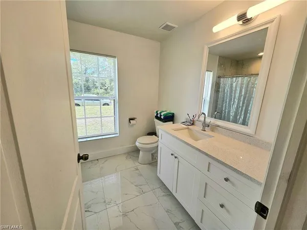 a spacious bathroom with a granite countertop sink a toilet and a mirror