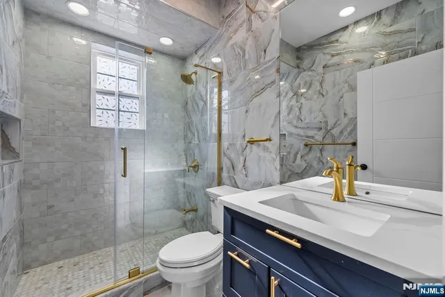 a bathroom with a granite countertop sink a mirror and shower