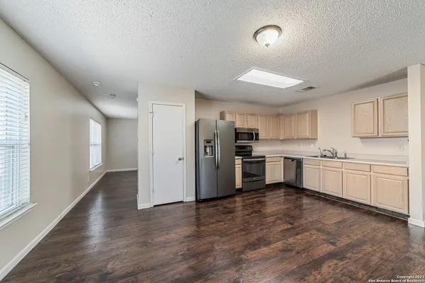 a kitchen with stainless steel appliances a refrigerator a sink dishwasher a stove and white cabinets with wooden floor