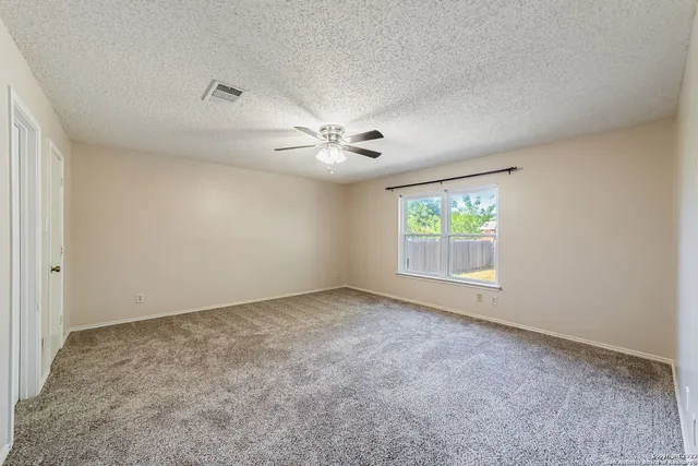 an empty room with windows and ceiling fan